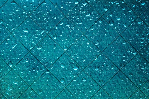 ガラスに纏わりつく雨粒の写真