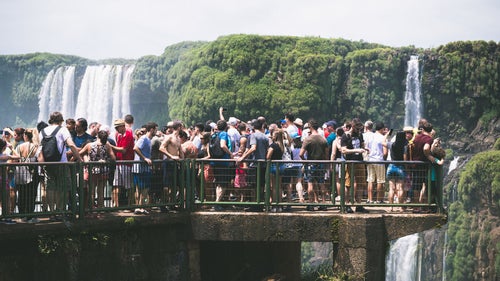 滝の上の遊歩道に群がるツアー客（南米大陸）の写真