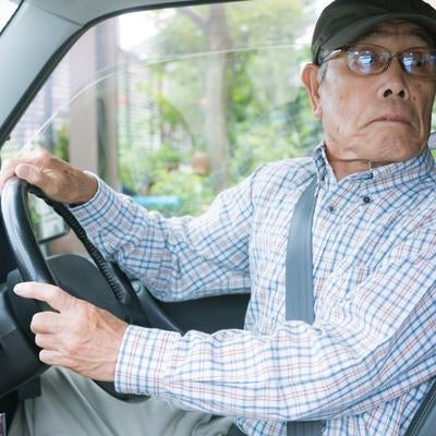 バック駐車で嫌な音が聞こえて慌てる高齢者の写真