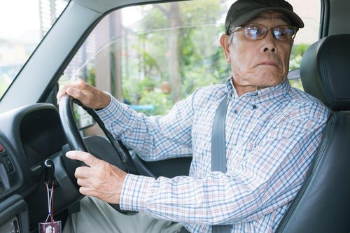 バック駐車で嫌な音が聞こえて慌てる高齢者の写真