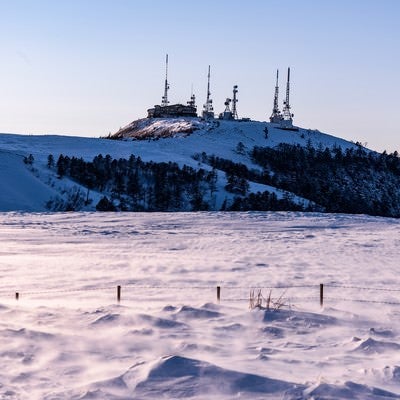 積雪の高台にそびえる電波塔の写真