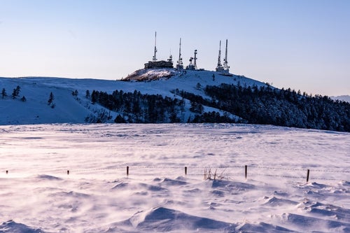 積雪の高台にそびえる電波塔の写真