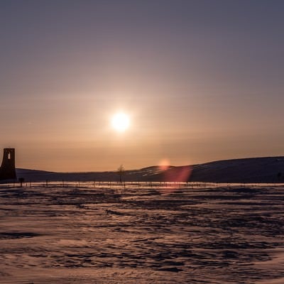 夕暮れの雪原と避難塔の写真