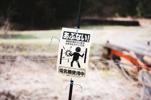 電気柵使用中の警告看板の写真