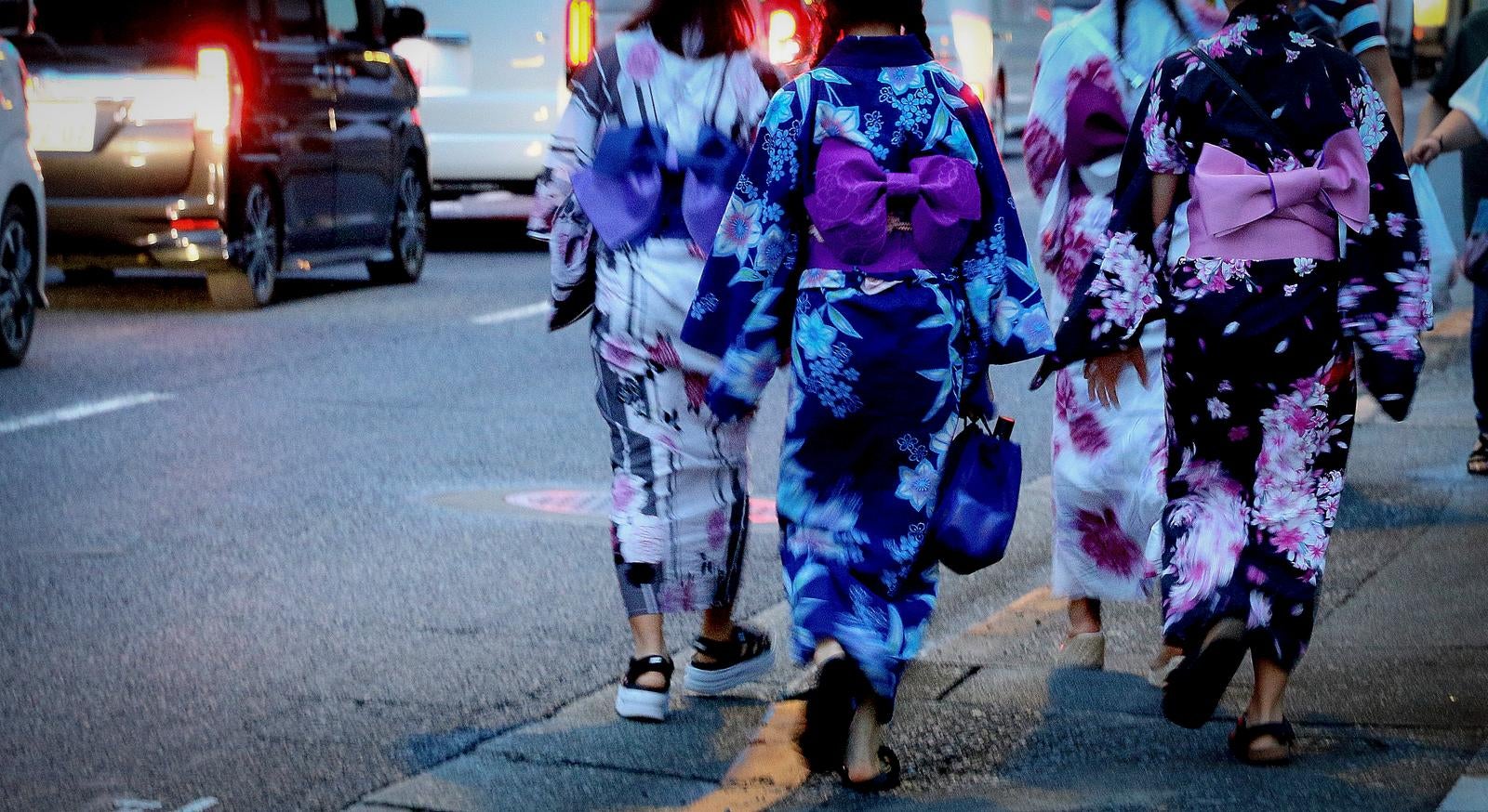 「夏の夕暮れ、浴衣姿で街を歩く女性達の後ろ姿」の写真