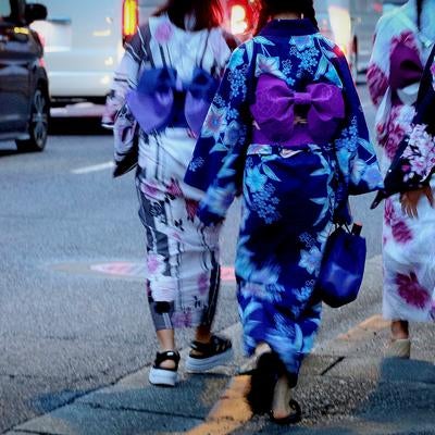 夏の夕暮れ、浴衣姿で街を歩く女性達の後ろ姿の写真