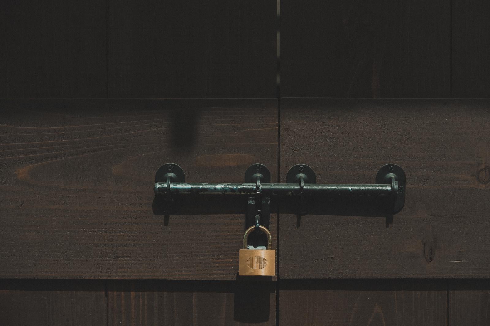 「木製の扉に取り付けられた閂と南京錠」の写真