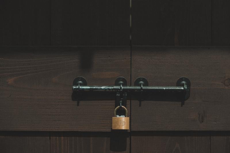 木製の扉に取り付けられた閂と南京錠の写真