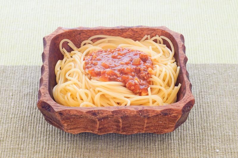 木製の器に盛りつけられたスパゲッティミートソースの写真
