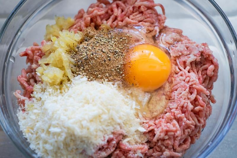 ハンバーグを作るのに合い挽き肉や卵などの材料をボウルに入れるの写真