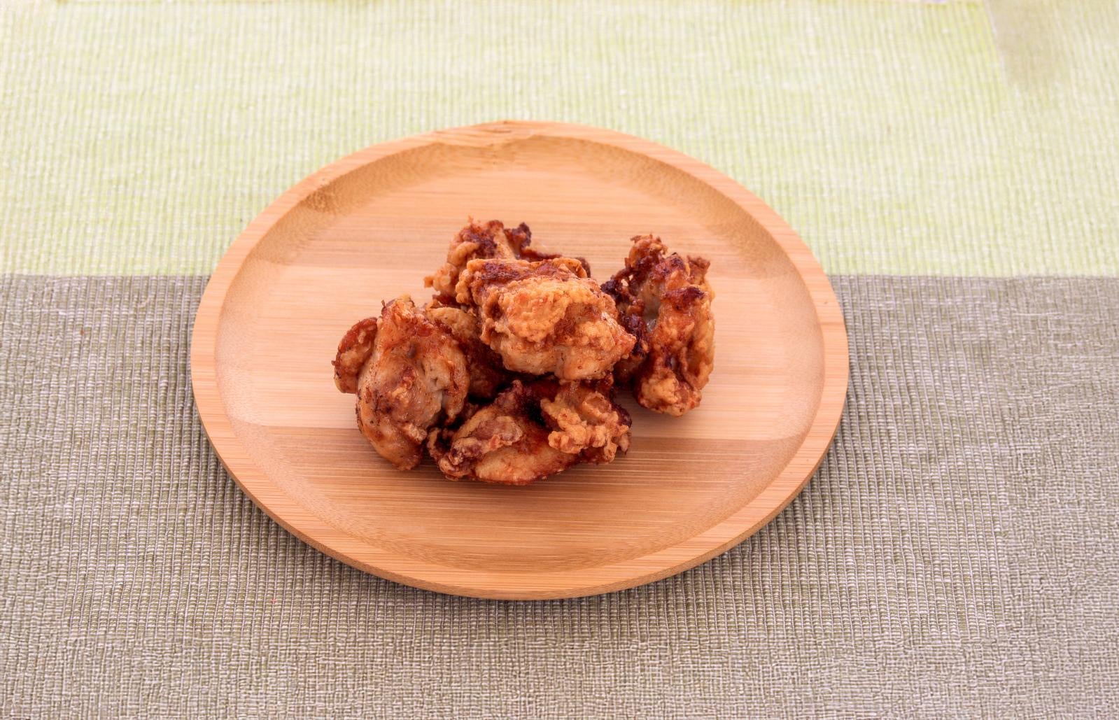 「木製の丸皿に盛られている鶏のから揚げ」の写真