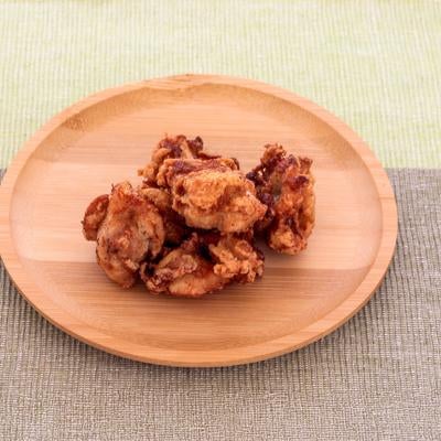 木製の丸皿に盛られている鶏のから揚げの写真