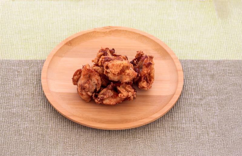 木製の丸皿に盛られている鶏のから揚げの写真