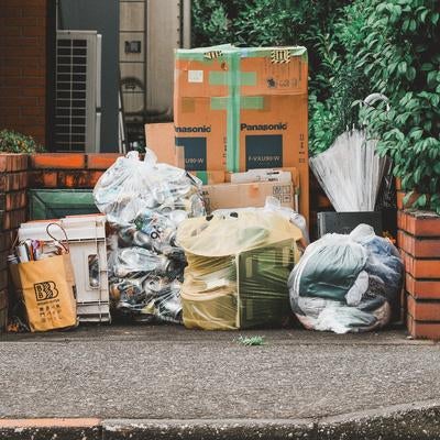 住宅街のごみ集積所に整然と並ぶ資源ごみと段ボールの写真