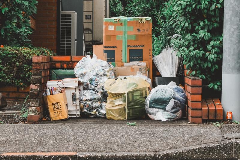 住宅街のごみ集積所に整然と並ぶ資源ごみと段ボールの写真
