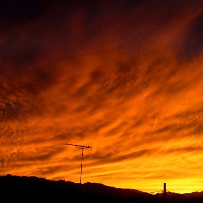 オレンジ色に染まった夜空と放送用アンテナのシルエットの写真