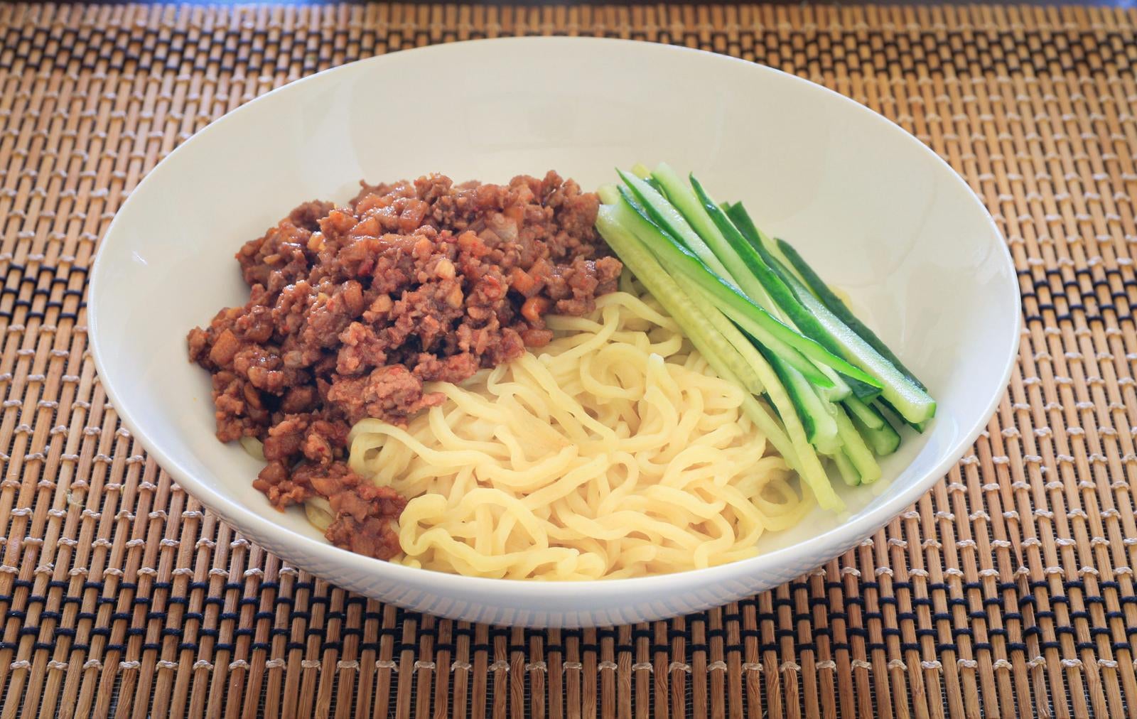 白い皿に中華麺と肉味噌、千切りきゅうりを盛り付けたジャージャー麺
