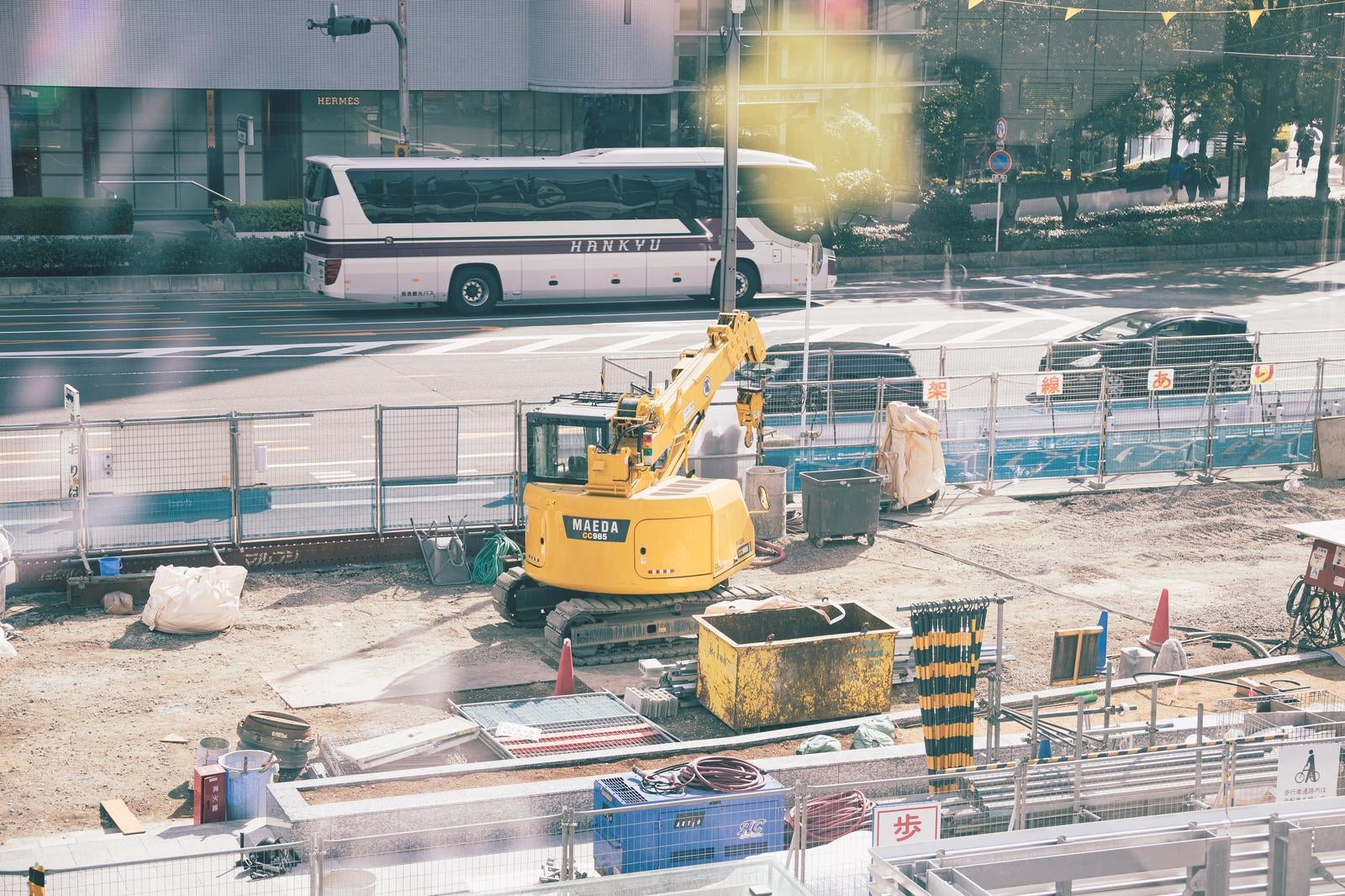 「大阪建築現場と通り抜けるバスの共演」の写真