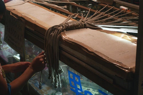 お祭りの出店で紐のうち1本を引くと吊るされた商品がもらえる系のくじ引き（千本引き）の写真