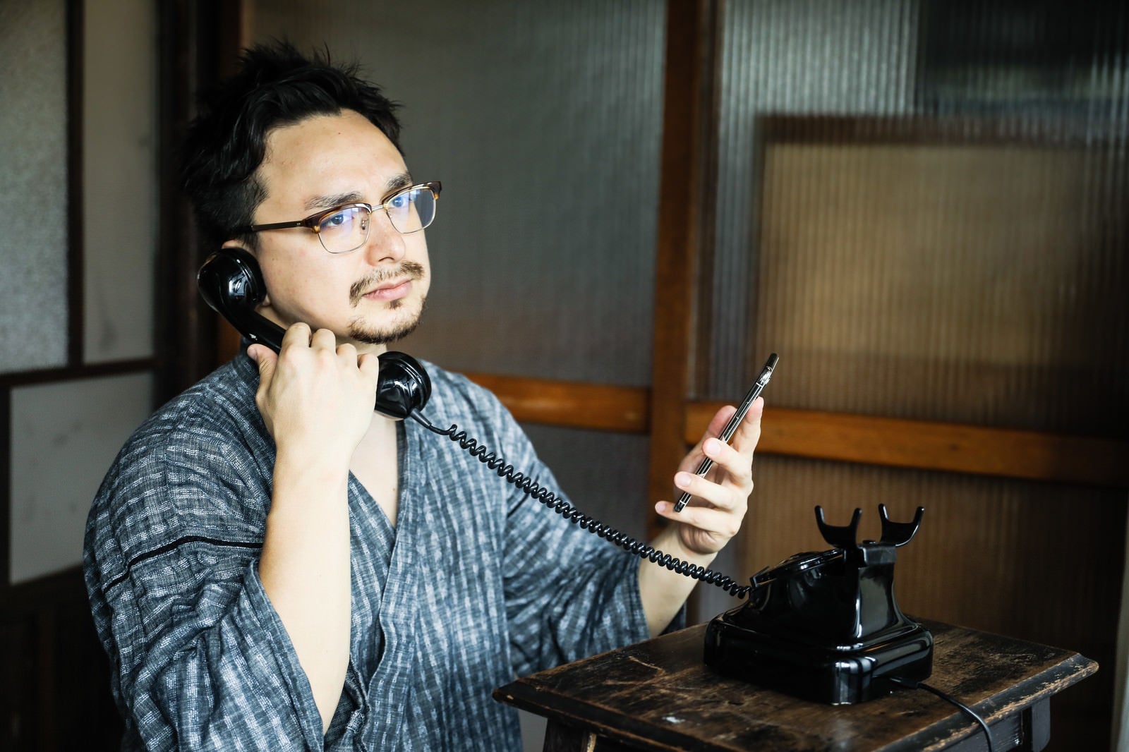 「スマホで連絡先を確認しながら黒電話を使う外国人観光客」の写真［モデル：Max_Ezaki］