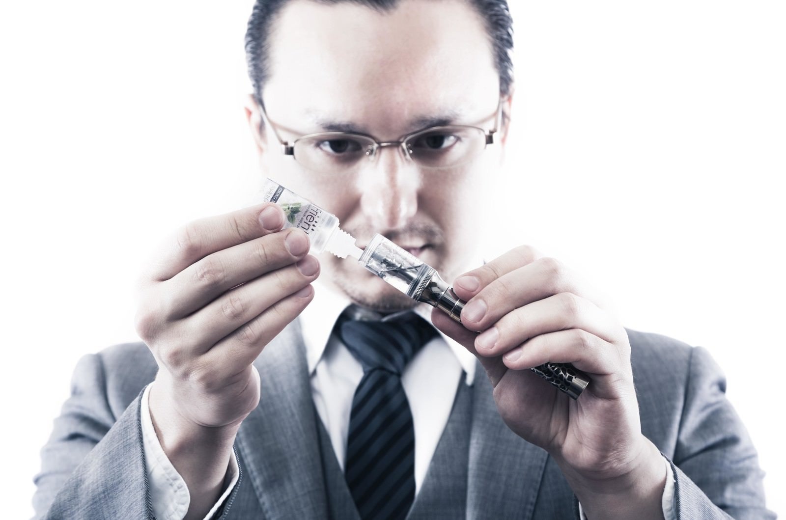 「電子タバコにリキッドを補充するビジネスマン」の写真［モデル：Max_Ezaki］
