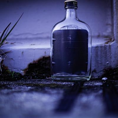 薄暗い路地に佇む空き瓶の写真