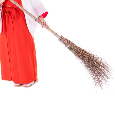 竹ほうきで掃き掃除をする巫女の足元の写真