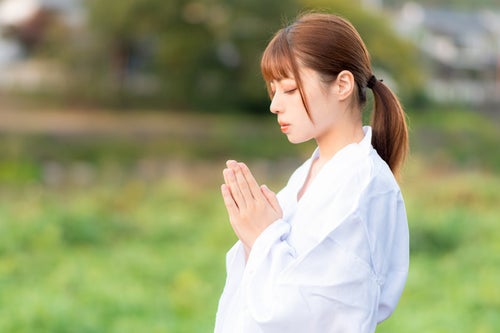 目を閉じてお祈りする巫女の写真