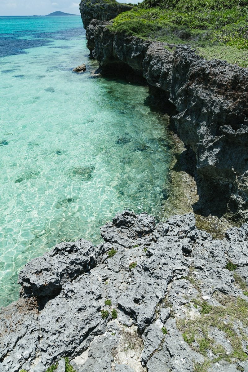 エメラルドグリーンの美しい海水と隆起珊瑚の写真