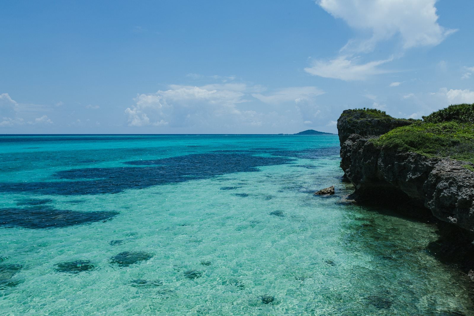 「宮古島の岩場から見下ろす透き通った美しいエメラルドブルーの海岸線」の写真