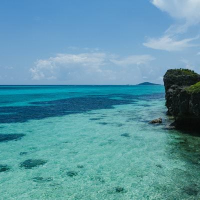 宮古島の岩場から見下ろす透き通った美しいエメラルドブルーの海岸線の写真