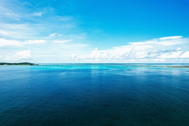 宮古島から望む伊良部大橋と透明度のエメラルドブルーの海の写真