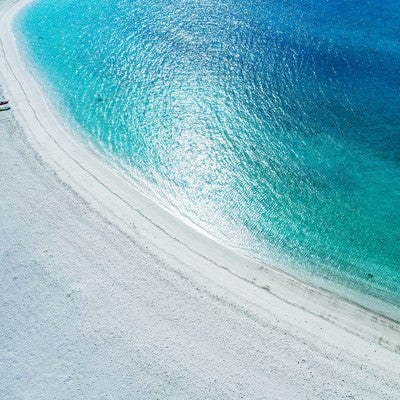 弧を描く白い砂浜の海水浴場の写真