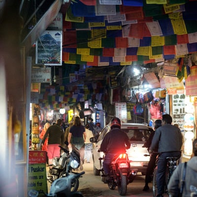 人でごった返す細い商店街に車とバイクが侵入する（ネパール）の写真