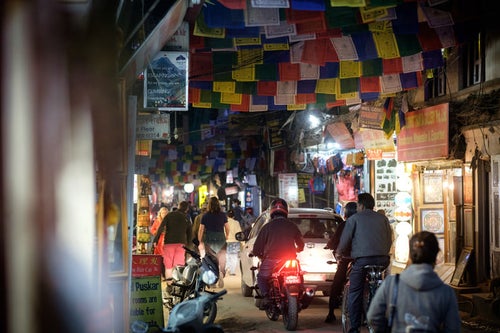 人でごった返す細い商店街に車とバイクが侵入する（ネパール）の写真