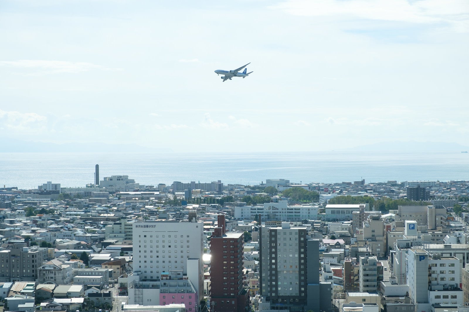 「街の上空を飛ぶ旅客機」の写真