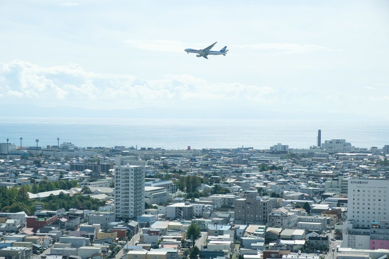 街並みと離陸した旅客機（函館空港）の写真