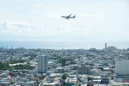 街並みと離陸した旅客機（函館空港）の写真