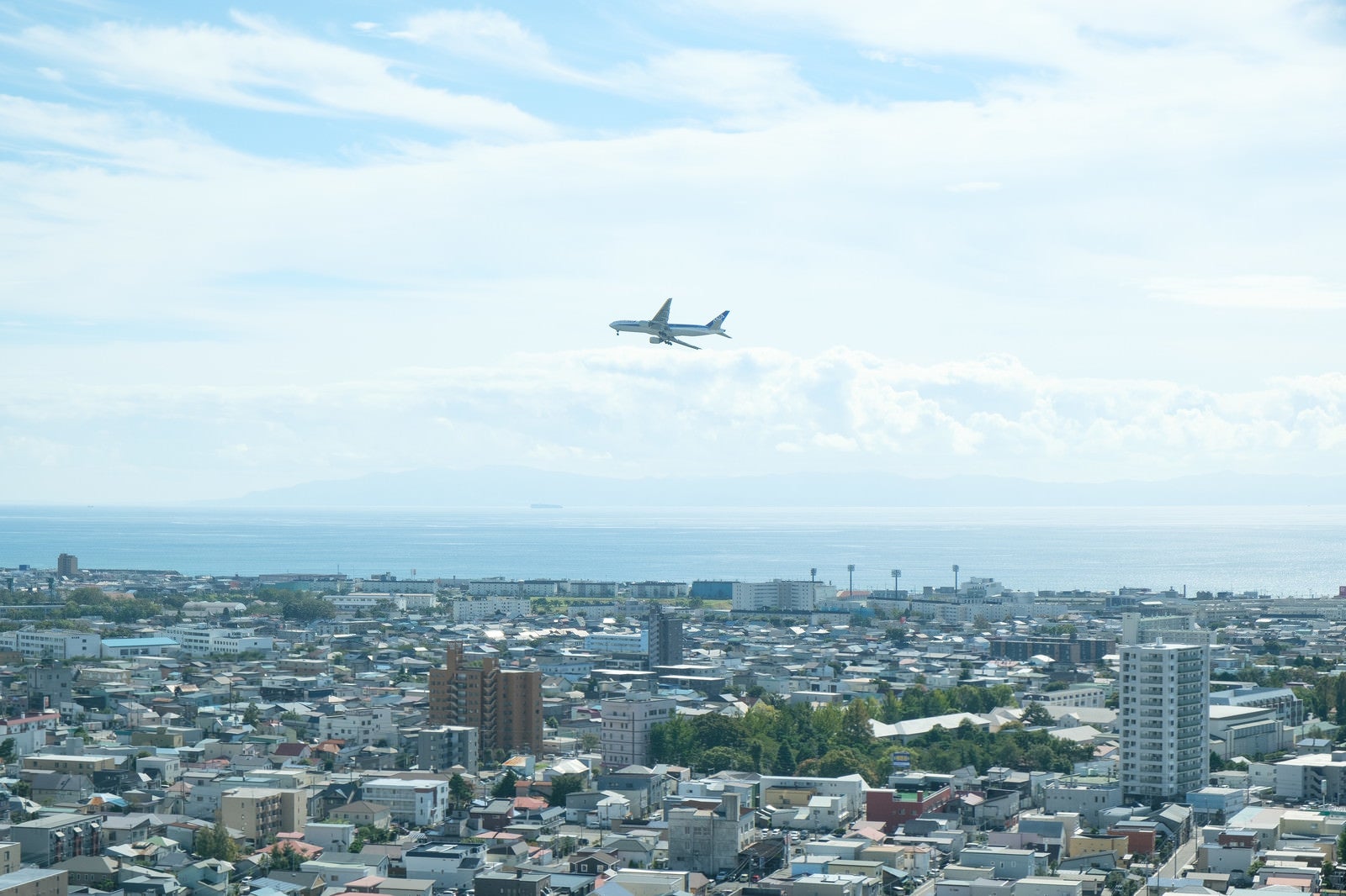 「市街地の上空を旋回する旅客機」の写真