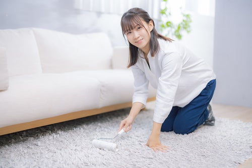 絨毯をコロコロで掃除する女性の写真
