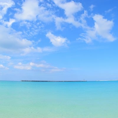 沖縄の海と遠くに見える防波堤の写真