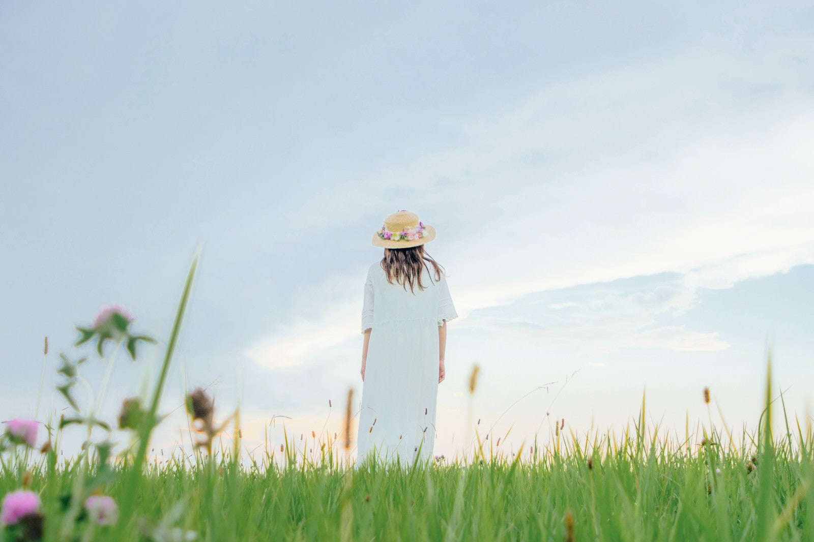 「草原で立ちつくす麦わら帽子の女性」の写真