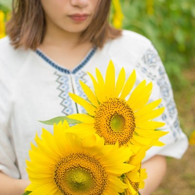 向日葵の花を抱えた女性の写真