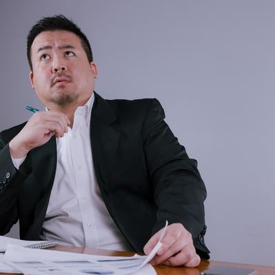仕事の書類に目を通しながら考え込むビジネスマンの素材