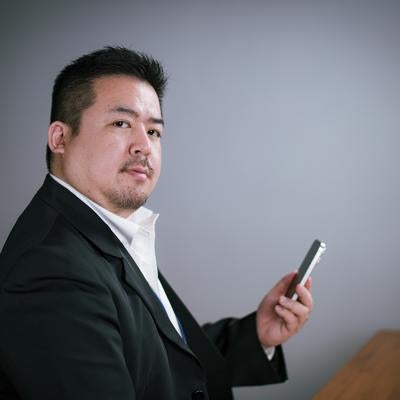 デスクサイドでスマホを操作してキリッの素材
