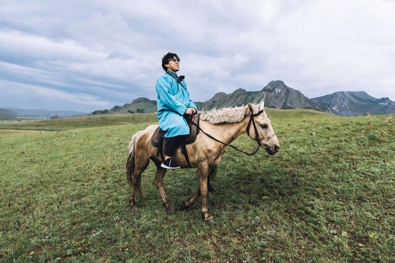 モンゴルの民族衣装を着用して乗馬するトラベラーの写真