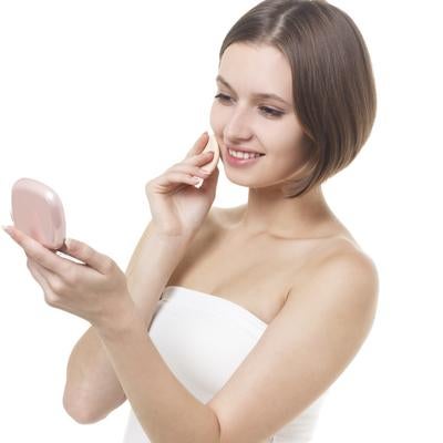 化粧直し中にコンパクトミラーで自分の顔を確認する女性の写真