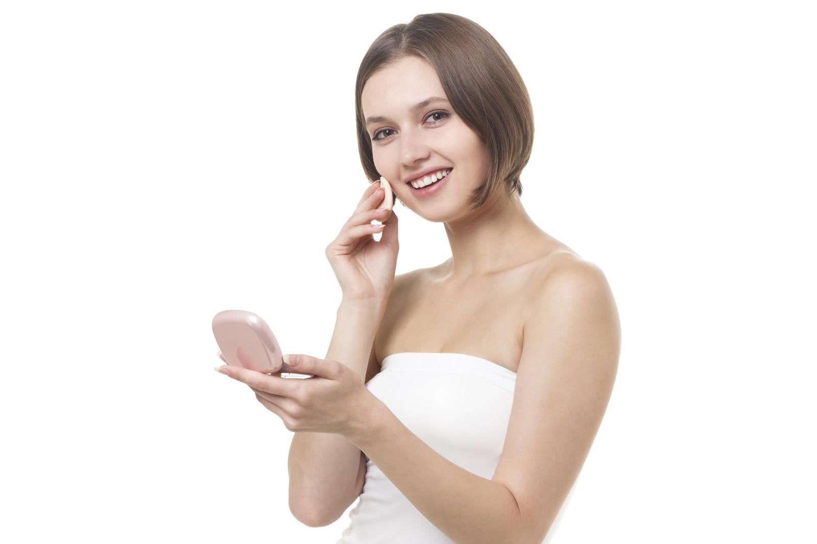 ピンク系のコンパクトミラーを持ち化粧直しをする女性［モデル：モデルファクトリー］