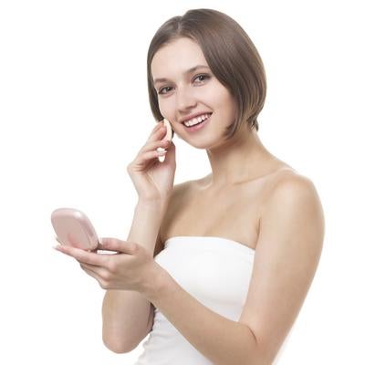 コンパクトミラーで肌を確認しメイク直しする女性の顔の写真