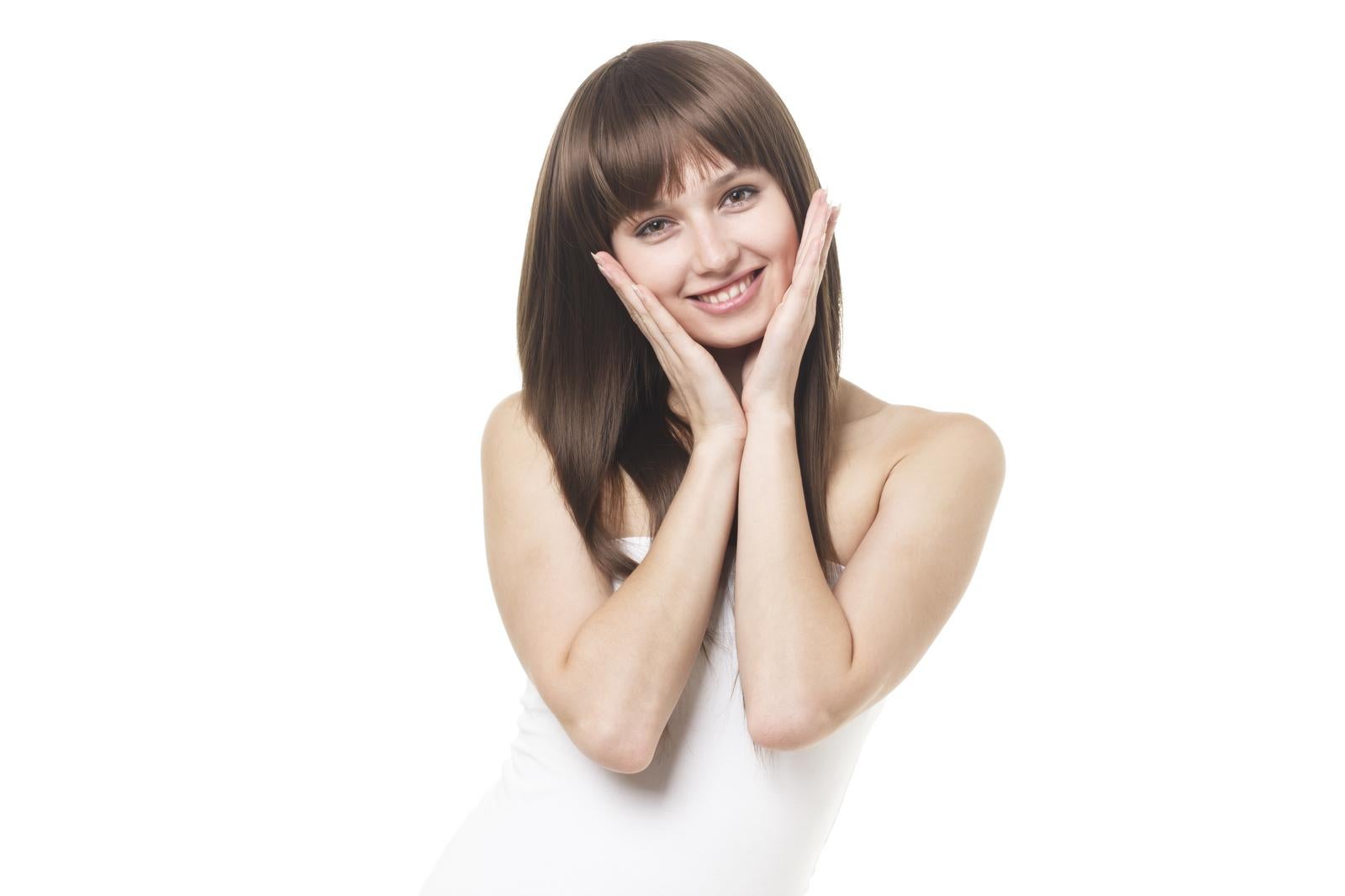 白背景の前で両手を頬に添えて笑顔を見せるストレートヘアの女性［モデル：モデルファクトリー］